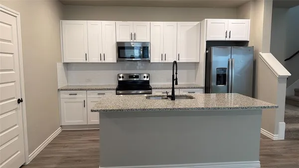a kitchen with stainless steel appliances granite countertop a sink a stove and refrigerator