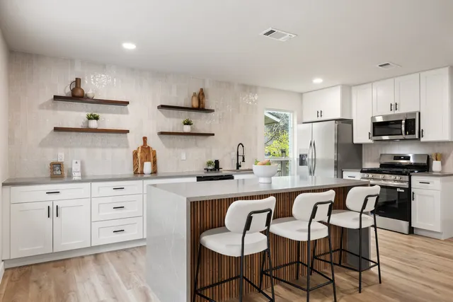 a kitchen with stainless steel appliances granite countertop a stove a sink dishwasher and a refrigerator with wooden floor