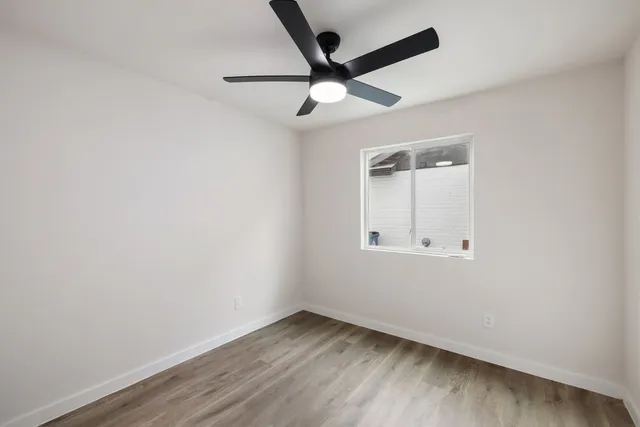 an empty room with a window and a ceiling fan