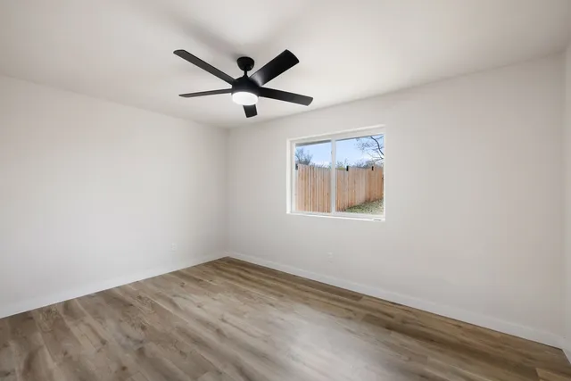 an empty room with a window and a fan