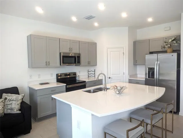 a kitchen with a sink a microwave a refrigerator and white cabinets