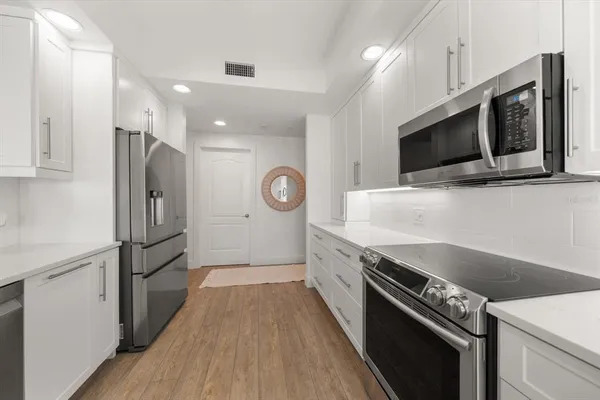 a kitchen with granite countertop a refrigerator and a stove top oven