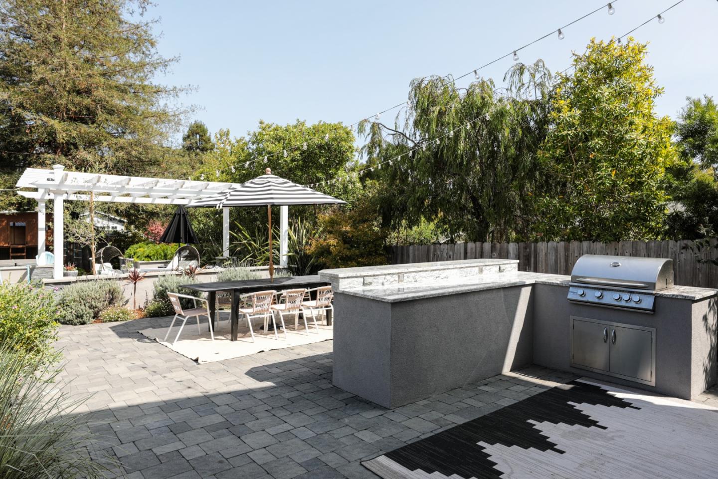 818 Crossway Road Burlingame, CA 94010 - Photo 44 of 50 a view of a patio with a dining table and chairs under an umbrella with large trees