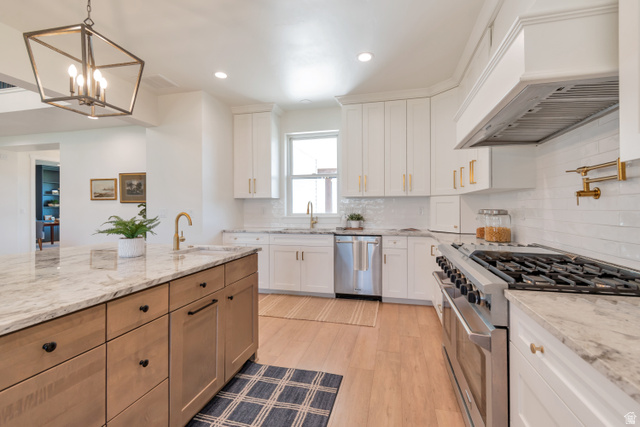 1820 West Farmhouse Flats Road Peoa, UT 84061 - Photo 17 of 79 Gourmet kitchen with a large central island, light wood-finish flooring, white cabinetry, integrated stainless steel appliances, and a tiled backsplash