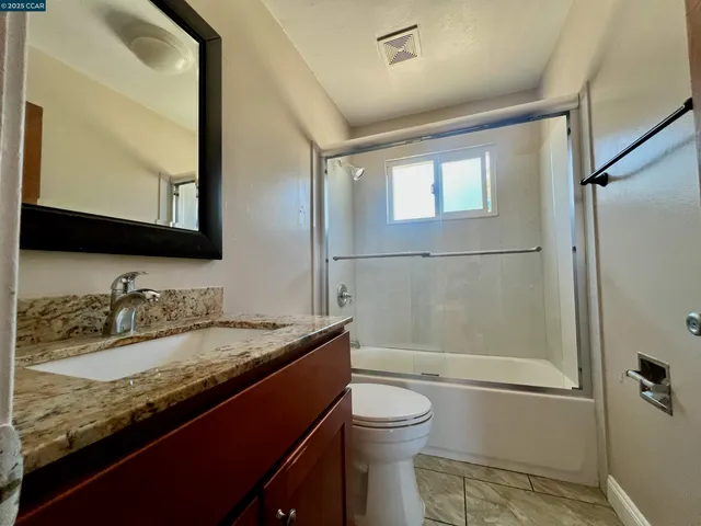 a bathroom with a granite countertop sink toilet and shower