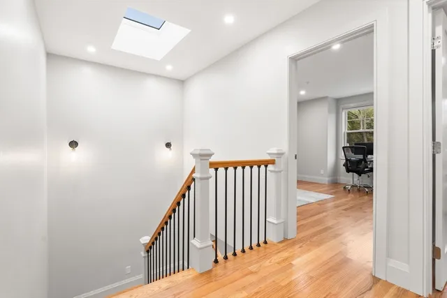 a view of a hallway with wooden floor and a bathroom