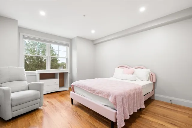 a bedroom with a bed and a couch with wooden floor