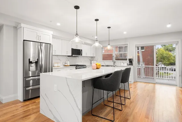 a kitchen with stainless steel appliances kitchen island granite countertop a refrigerator a stove a sink dishwasher and a wooden cabinets with wooden floor