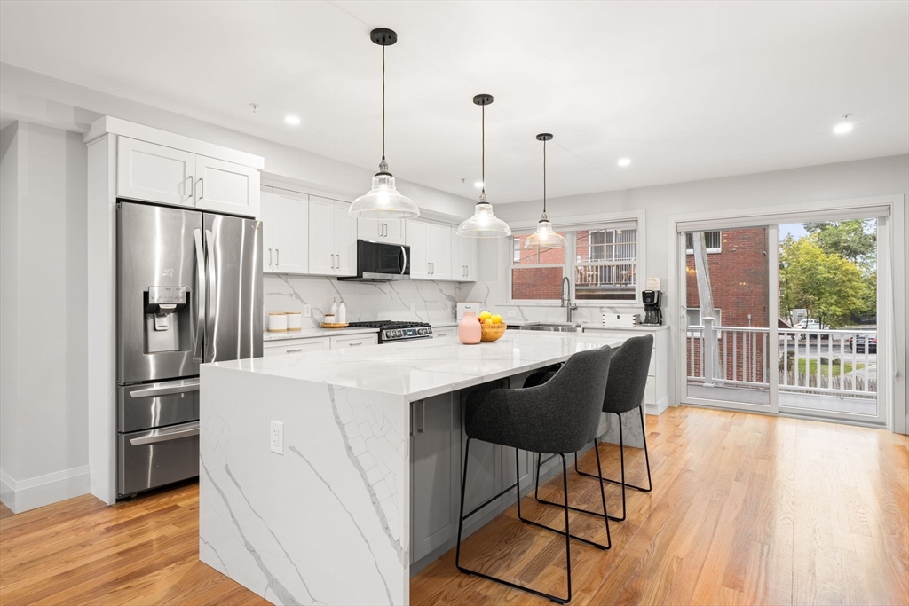 114 Broad Street, Unit D Weymouth, MA 02188 - Photo 3 of 41 a kitchen with stainless steel appliances kitchen island granite countertop a refrigerator a stove a sink dishwasher and a wooden cabinets with wooden floor