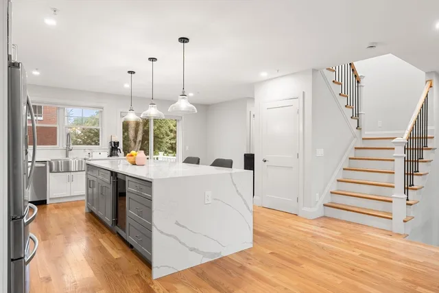 a large white kitchen with wooden floor and a ceiling fan