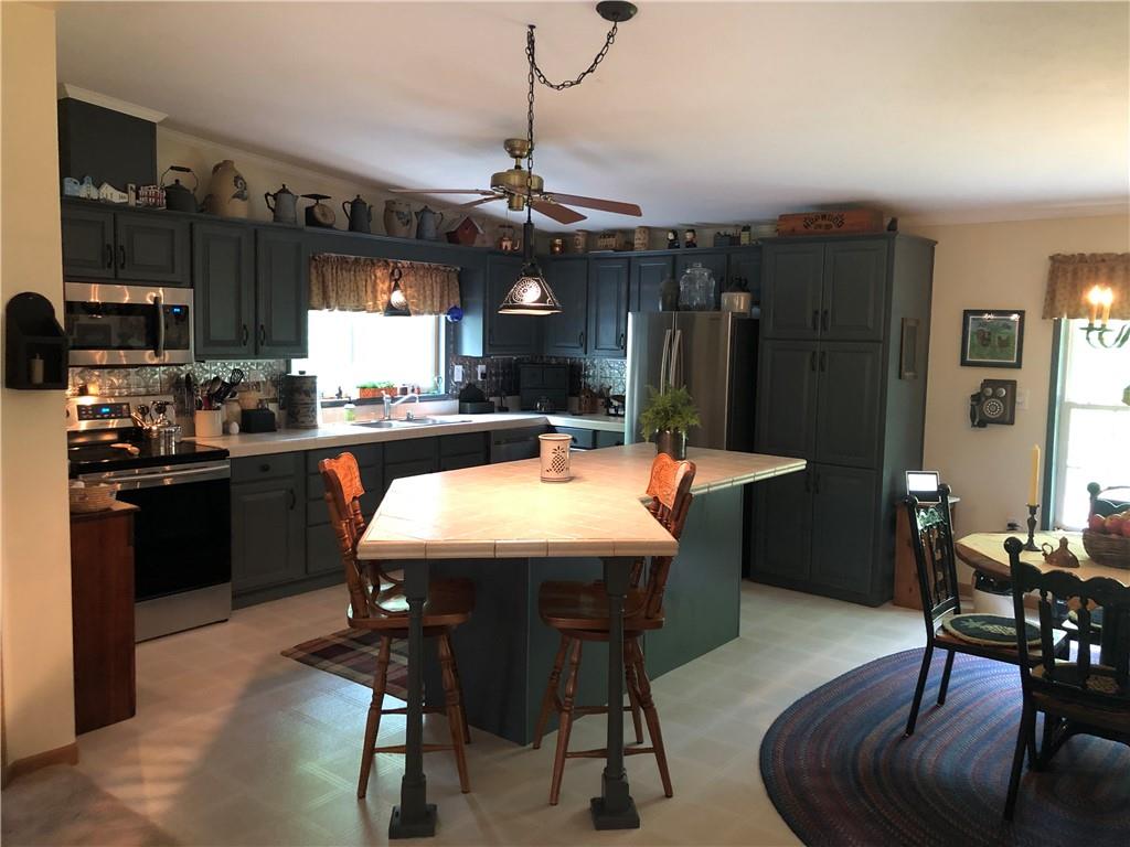 661 Nelson Road Farmington, PA 15437 - Photo 21 of 50 a kitchen with stainless steel appliances granite countertop a sink a stove a refrigerator a dining table and chairs with wooden floor