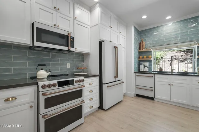 a kitchen with white cabinets and stainless steel appliances