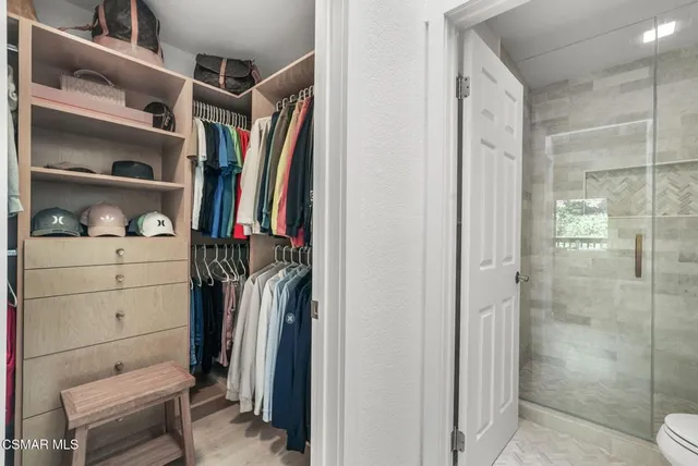 a view of walk in closet with clothes and shoes