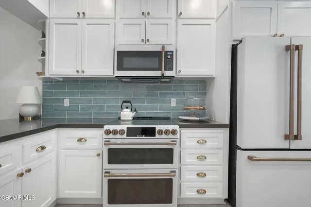 a kitchen with stainless steel appliances white cabinets and a refrigerator