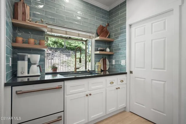 a kitchen with white cabinets and a window