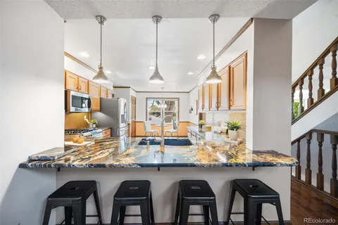 a kitchen with stools a sink and chairs