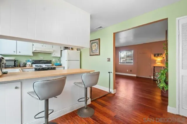 a kitchen with kitchen island a dining table chairs and a refrigerator