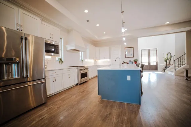 a kitchen with stainless steel appliances granite countertop a refrigerator a sink dishwasher and a oven with wooden floors