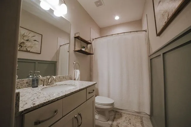 a bathroom with a granite countertop sink a toilet and a shower