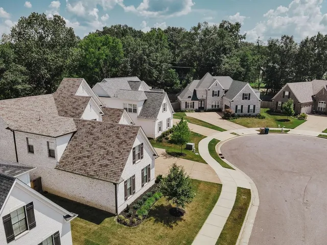 an aerial view of a house with swimming pool and large trees