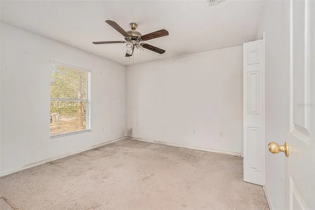 an empty room with a ceiling fan and a window