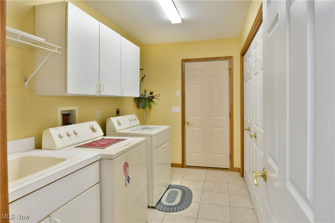 1997 East County Line Road Mineral Ridge, OH 44440 - Photo 31 of 35 Laundry area with sink, cabinets, washing machine and dryer, and light tile patterned floors