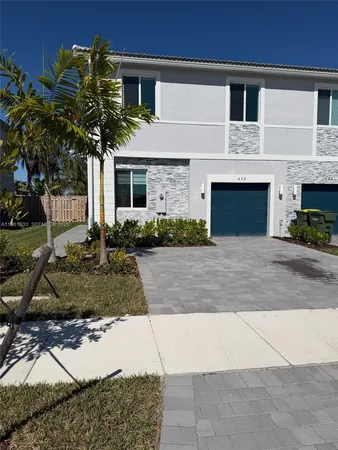 a front view of a house with a yard and potted plants