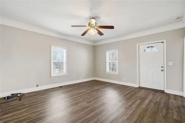a view of an empty room with wooden floor and a window