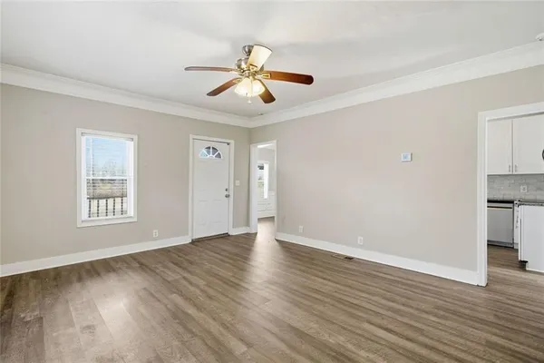 an empty room with wooden floor cabinet and windows