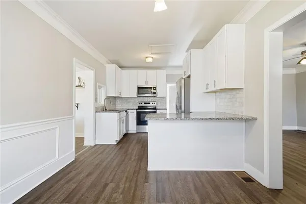 a kitchen with granite countertop a refrigerator and a stove top oven