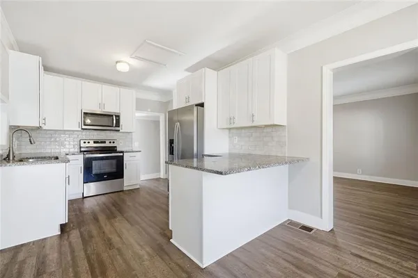 a kitchen with granite countertop a stove top oven a sink and a refrigerator