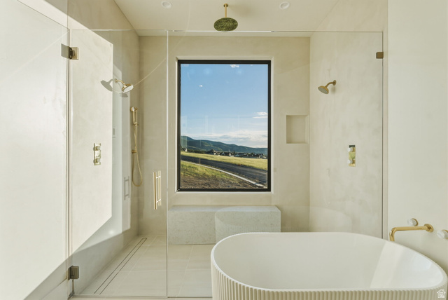 923 North Emery Lane Elk Ridge, UT 84651 - Photo 31 of 101 Freestanding soaking tub with fluted exterior, walk-in shower with dual shower heads, and large window showcasing mountain scenery