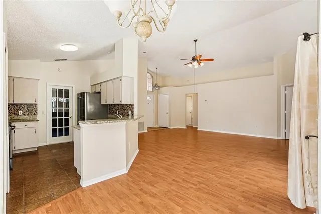 a view of a kitchen with refrigerator and wooden floor