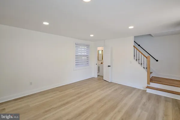 a view of an empty room with wooden floor and stairs