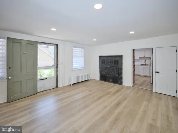 a view of an empty room with a window and a kitchen