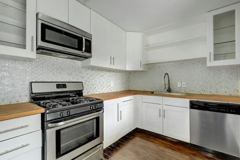 a kitchen with cabinets stainless steel appliances and wooden floor