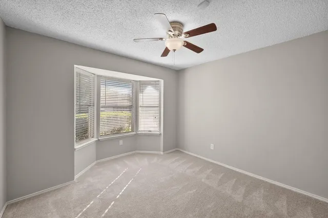 an empty room with ceiling fan and windows