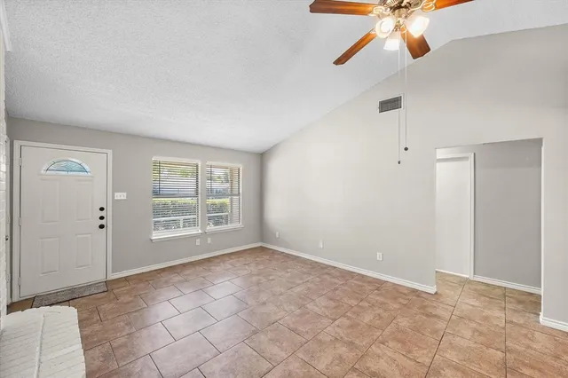 an empty room with windows and fan