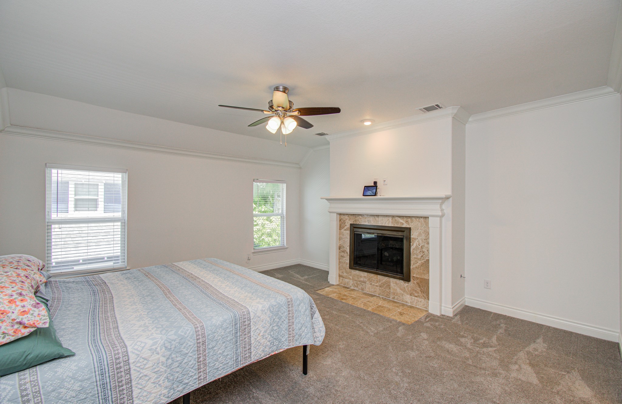 6621 North Main Street Houston, TX 77009 - Photo 15 of 41 Primary suite bedroom with carpeted flooring, featuring a cozy fireplace located on the second floor. Ample natural light from two windows enhances the room's inviting ambiance.