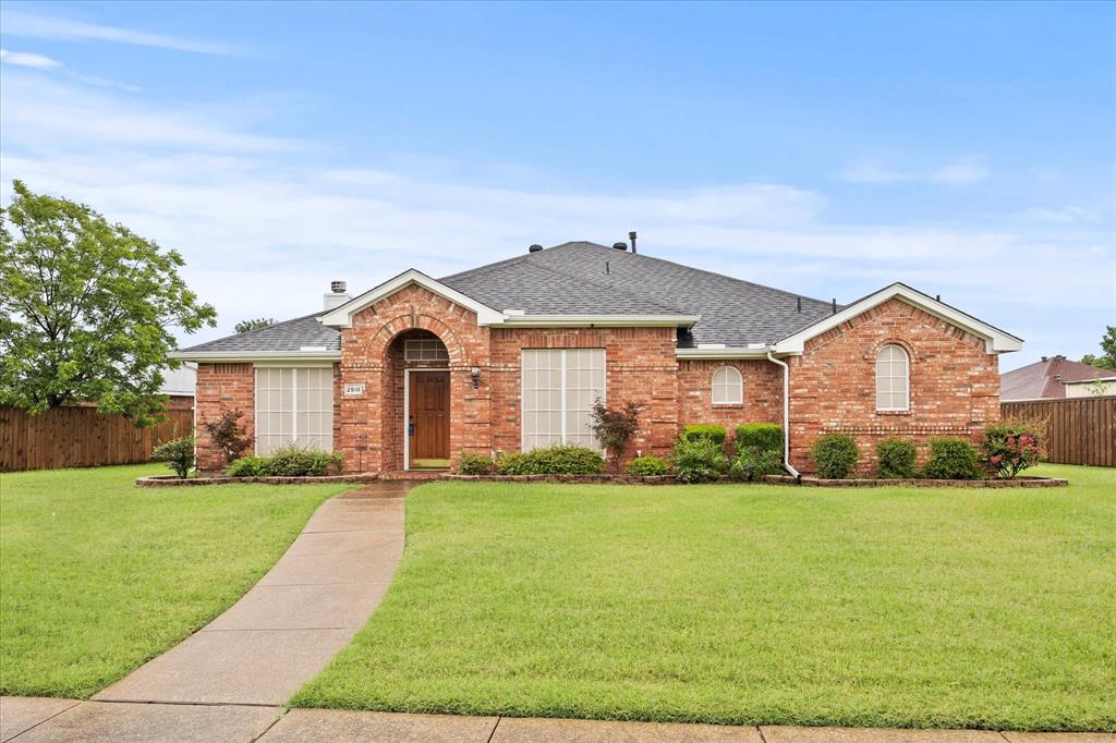 View of front facade featuring brick siding, roof with shingles, and a chimney