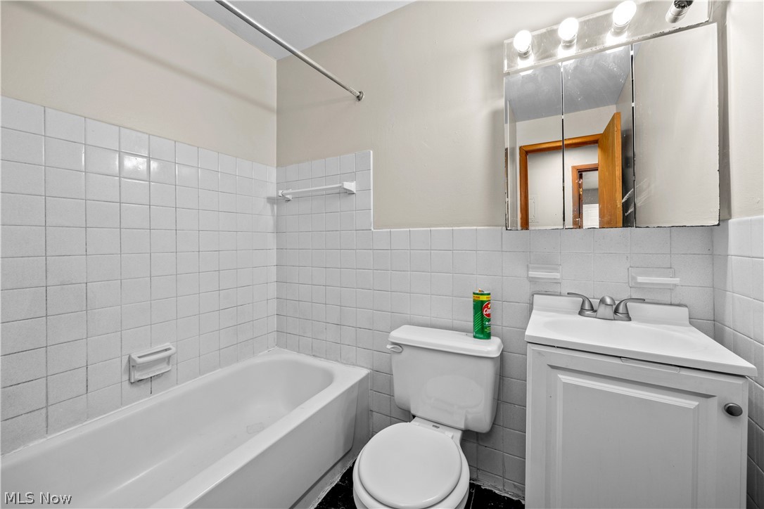 5370 Lee Road, Unit 302 Maple Heights, OH 44137 - Photo 20 of 29 Bathroom with vanity, tile walls, bathing tub / shower combination, and a wainscoted wall