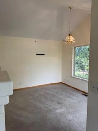 an empty room with windows and chandelier fan