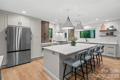 a kitchen with granite countertop a table chairs refrigerator and microwave