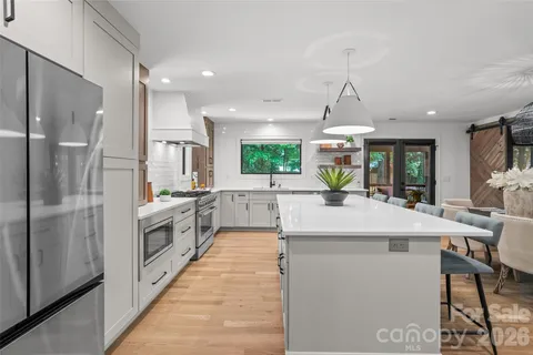 a large kitchen with kitchen island a large counter top space a sink stainless steel appliances and cabinets