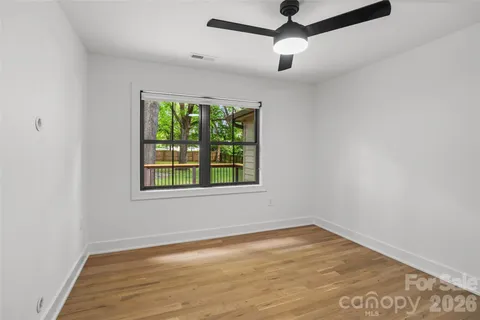 an empty room with a window and a ceiling fan