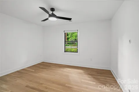 a view of empty room with window and ceiling fan
