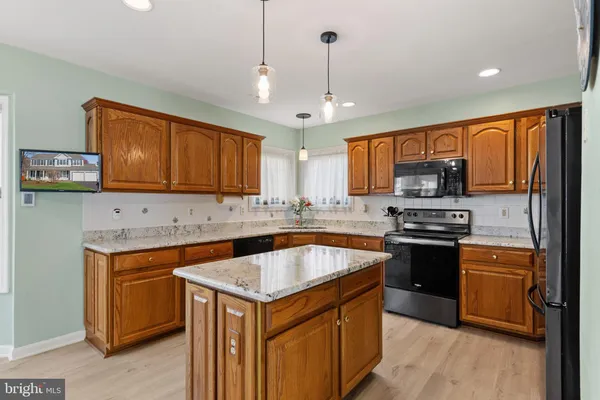 a kitchen with stainless steel appliances granite countertop refrigerator a stove top oven a sink dishwasher and wooden cabinets with wooden floor