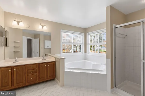 a spacious bathroom with a tub sink shower and mirror