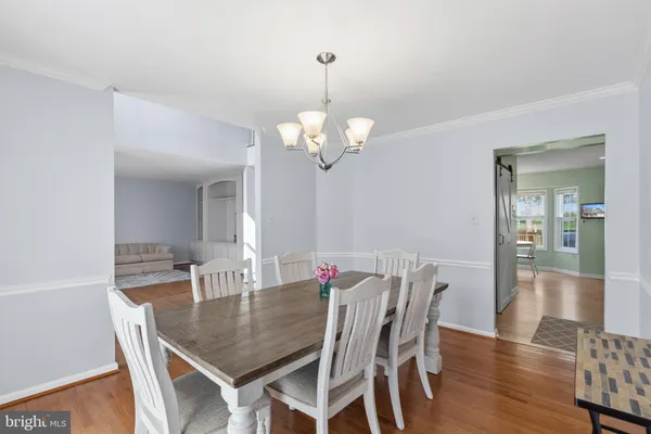 a dining room with wooden floor a chandelier a wooden table and chairs
