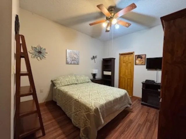 a bed sitting in a bedroom and a flat tv screen on dresser